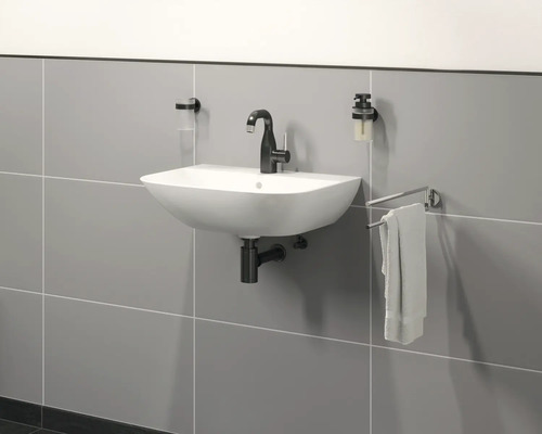 Wastafel aan de wand met kraan, zeepdispenser en handdoekhouder voor een betegelde muur