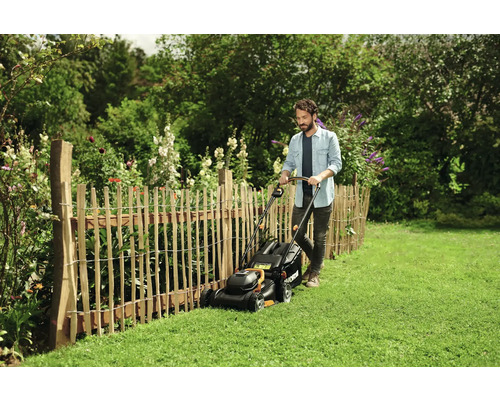Man maait gazon met een grasmaaier in een tuin
