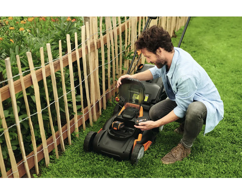 Man verwisselt de batterij van een gazonmaaier in de tuin.