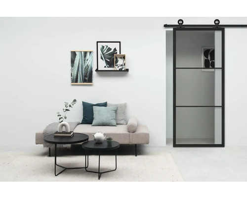 Woonkamer met schuifdeur, bank, salontafels en wanddecoraties.
