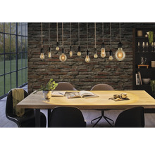 Eetkamer met eettafel, stoelen en hanglampen voor een bakstenen muur