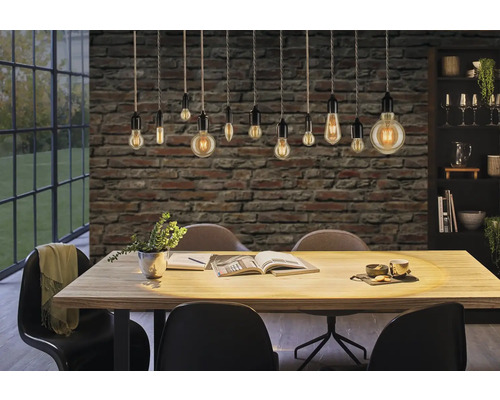 Eetkamer met eettafel, stoelen en hanglampen voor een bakstenen muur