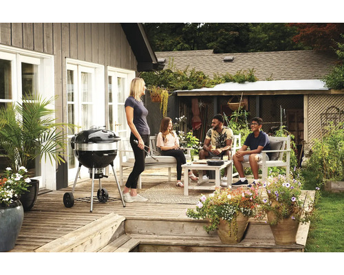 Buitenscène met barbecue, mensen en tuinmeubelen op een terras.