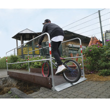 Een persoon fietst over een brug met een reling.