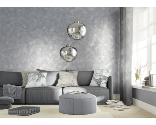 Woonkamer met bank, kussens, kruk en decoratieve wanddecoratie.