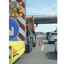 File op de snelweg met waarschuwingsaanhanger en pylonen