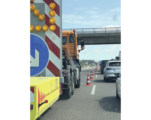 File op de snelweg met waarschuwingsaanhanger en pylonen