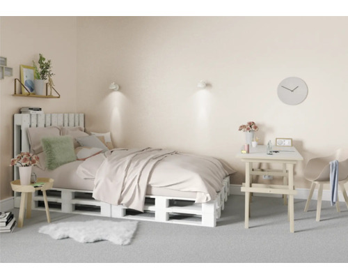 Slaapkamer met bed van houten pallets, bureau en stoel