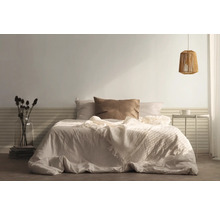 Slaapkamer met bed, kussens, sprei, nachtkastje en lamp