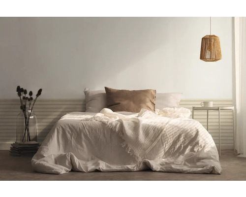 Slaapkamer met bed, kussens, sprei, nachtkastje en lamp