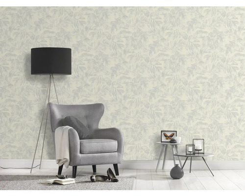 Een kamer met een patroonbehang, een fauteuil en een staande lamp.