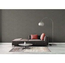Woonkamer met grijs textielbehang, bank, lamp en tapijt