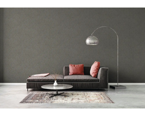 Woonkamer met grijs textielbehang, bank, lamp en tapijt