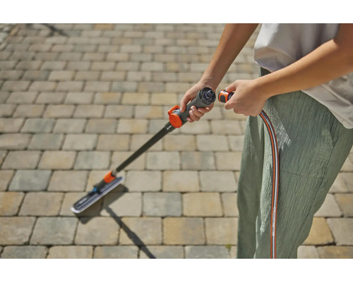 Een persoon verbindt een terrasreiniger met een tuinslang voor het schoonmaken van buitenruimtes.