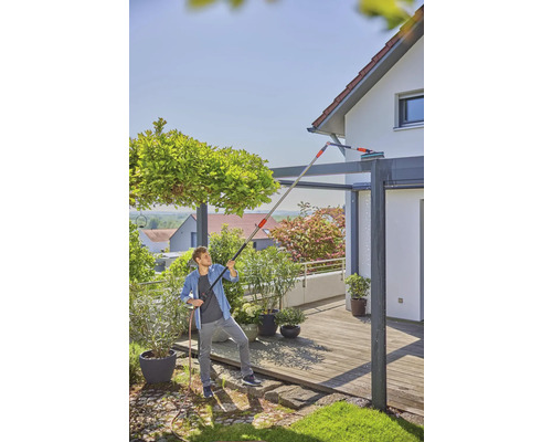 Man reinigt een terrasoverkapping met een telescopische stang en waterslang.