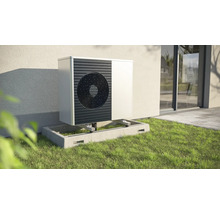 Buitenwarmtepomp op betonnen fundering in de tuin