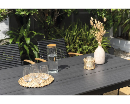 Tuinsetting met tafel, stoelen, glazen, waterkan, kaars en decoratie.