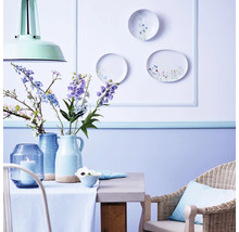 Decoratieve eethoek met tafel, stoel, vazen, bloemen en wandborden