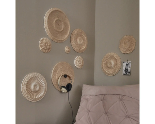 Wanddecoratie met sierrozetten in een slaapkamer, hoofdtelefoon aan de muur