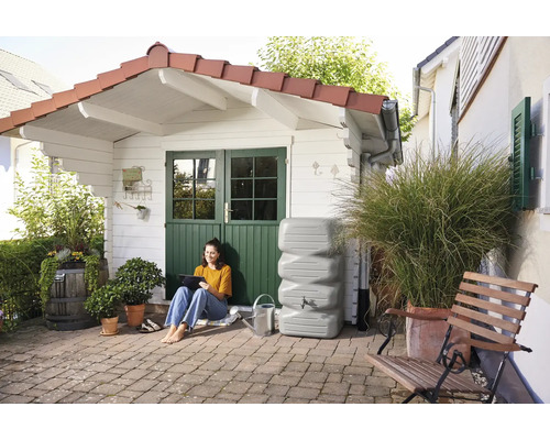 Tuinaanzicht met waterreservoir, vrouw met tablet en tuinhuis