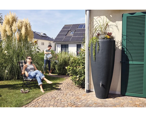 Tuinscène met regenton, man die water geeft en vrouw in een ligstoel