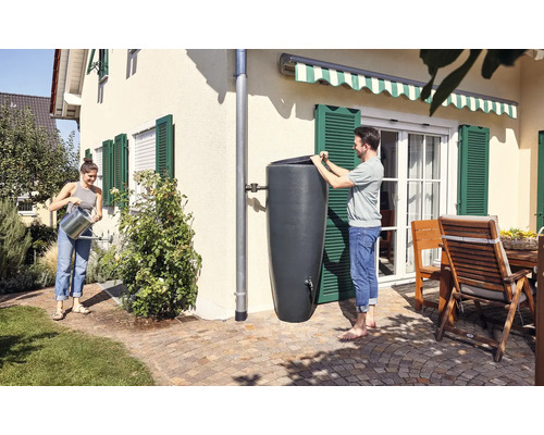 Personen gebruiken een regenton voor tuinbewatering in een zonnige tuin.