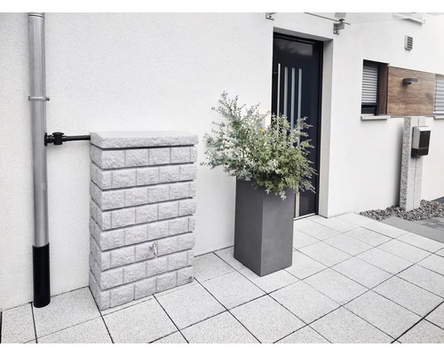 Watertank met steenlook naast regenpijp en plantenbak voor een huis