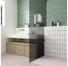 Badkamer met groene en witte wandtegels, wastafel en houten onderkast