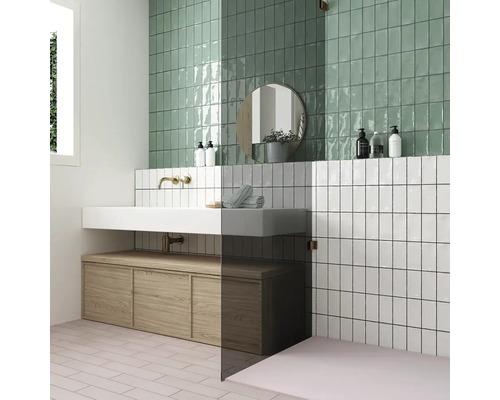 Badkamer met groene en witte wandtegels, wastafel en houten onderkast