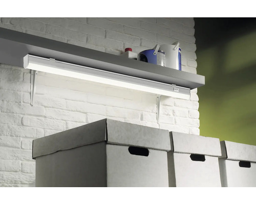 Plank met werklamp boven kartonnen dozen tegen een bakstenen muur