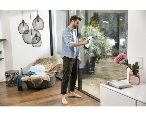 Man maakt ramen schoon met een raamstofzuiger in een heldere kamer