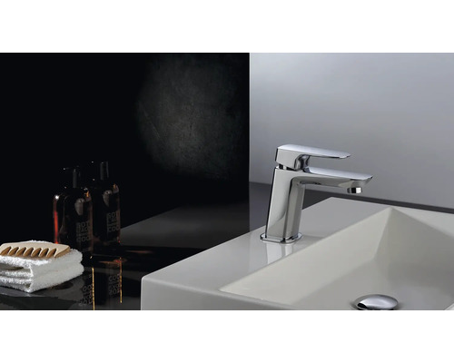 Wastafelkraan op een wastafel met handdoek en cosmetische producten