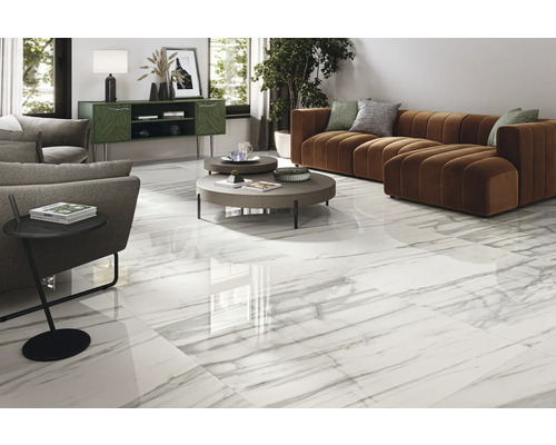 Lichte woonkamer met witte tegels in marmerlook, bank en bijzettafel.
