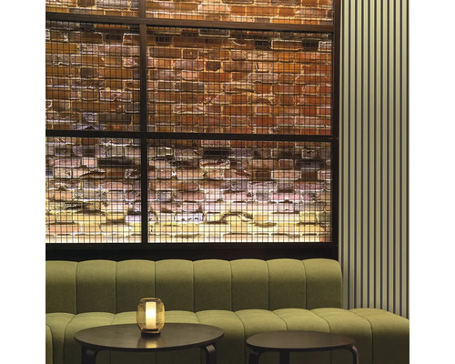 Interieur met bank, tafels en decoratieve bakstenen muur achter een metalen rooster