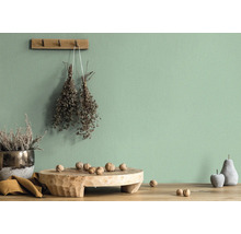 Wanddecoratie met gedroogde bloemen en decoratieobjecten op een houten tafel voor een groene muur