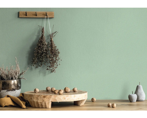 Wanddecoratie met gedroogde bloemen en decoratieobjecten op een houten tafel voor een groene muur