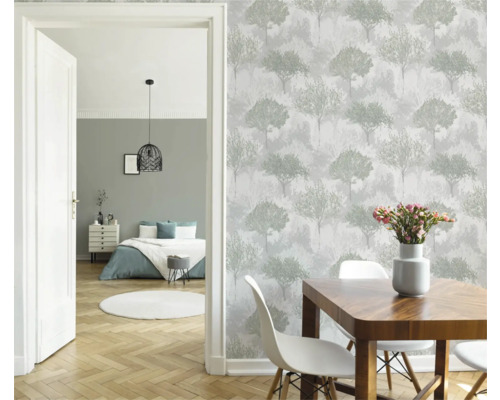 Eetkamer met houten tafel, witte stoelen en behang met boommotief.