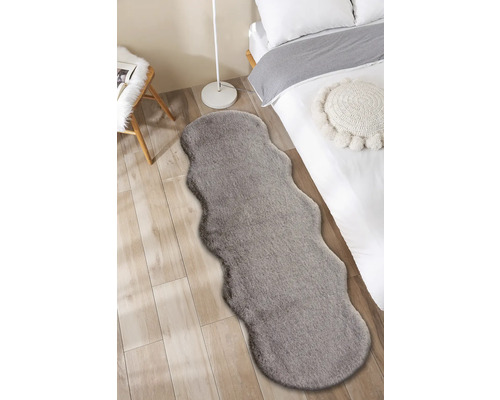 Interieurfoto van een slaapkamer met een bed en een grijs tapijt in een harig design.