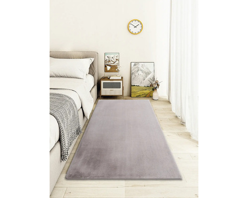 Grijs tapijt in slaapkamer met bed, nachtkastje en decoratie