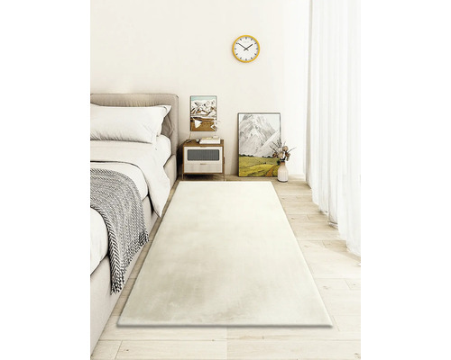 Lichte slaapkamer met bed, nachtkastje en lang, rechthoekig tapijt