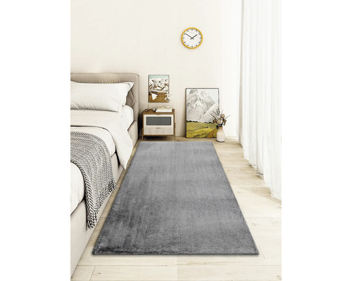 Grijs tapijt in slaapkamer met bed en nachtkastje