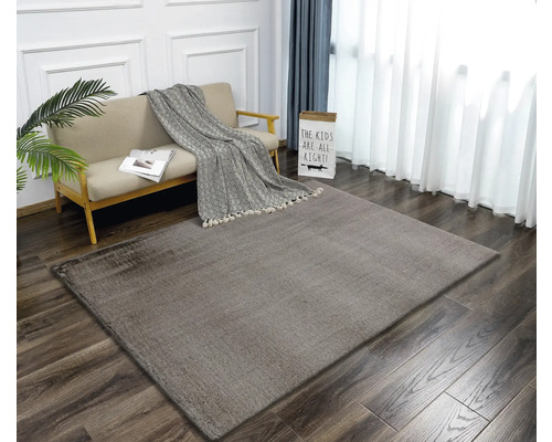 Woonkamer met bank, deken en rechthoekig vloerkleed op houten vloer