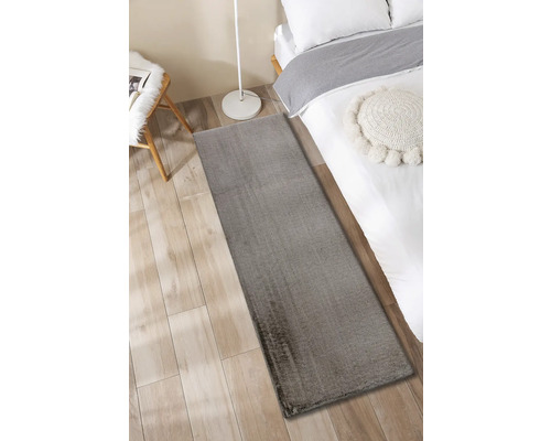 Grijs tapijt naast een bed op een houten vloer