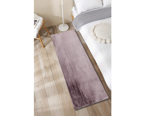 Modern tapijt in slaapkamer op houten vloer naast bed en lamp