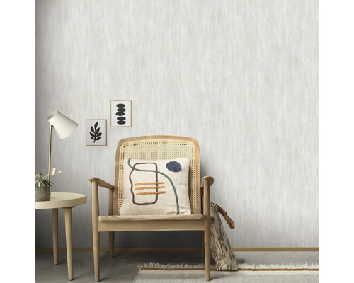 Scene met rotan stoel, tafel, lamp en behang met patroon op de achtergrond.