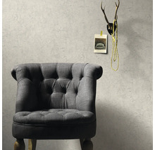 Grijze fauteuil voor een gestructureerde muur met decoratie