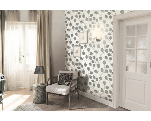 Woonkamer met bladerbehang, fauteuil en deur