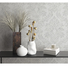 Decoratief stilleven met vazen, sierplanten, kaars en boek op een console voor een gedessineerd behang