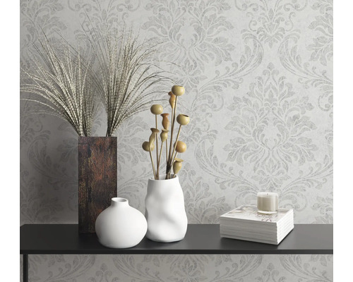 Decoratief stilleven met vazen, sierplanten, kaars en boek op een console voor een gedessineerd behang