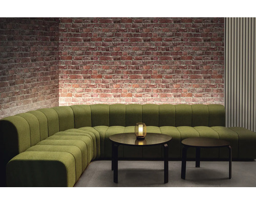 Kameroverzicht met groene modulaire bank, twee ronde tafels en bakstenen muur